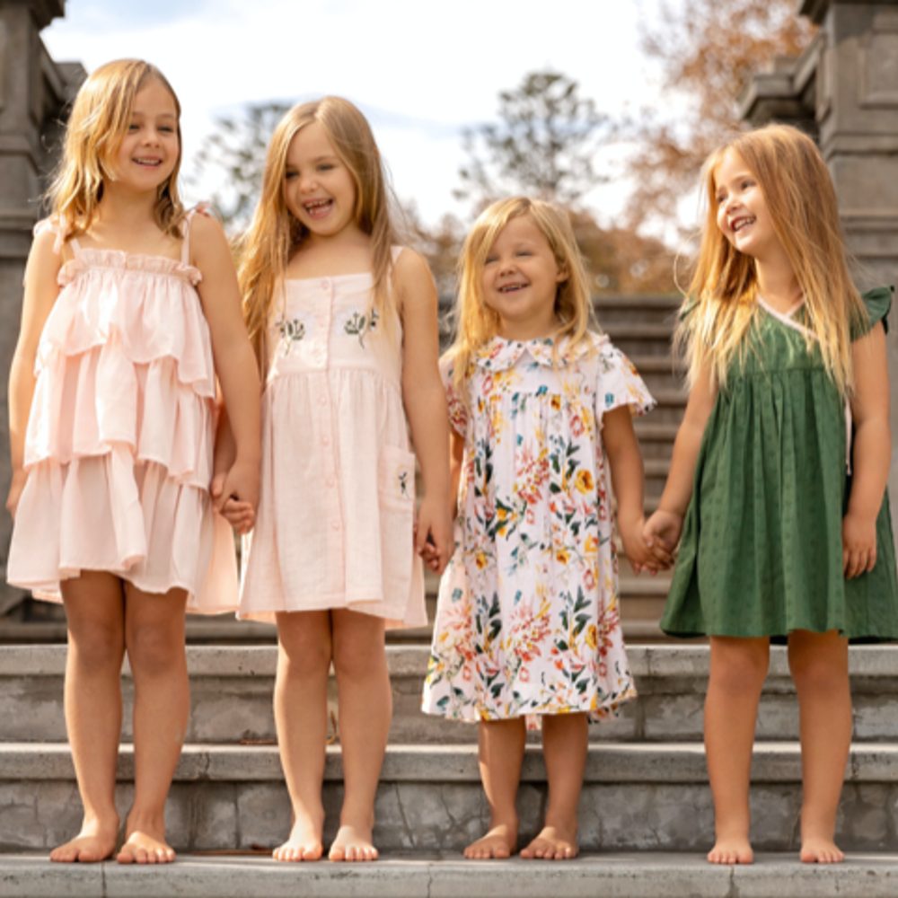 Four young girls in dresses stood outside at the bottom of some steps 