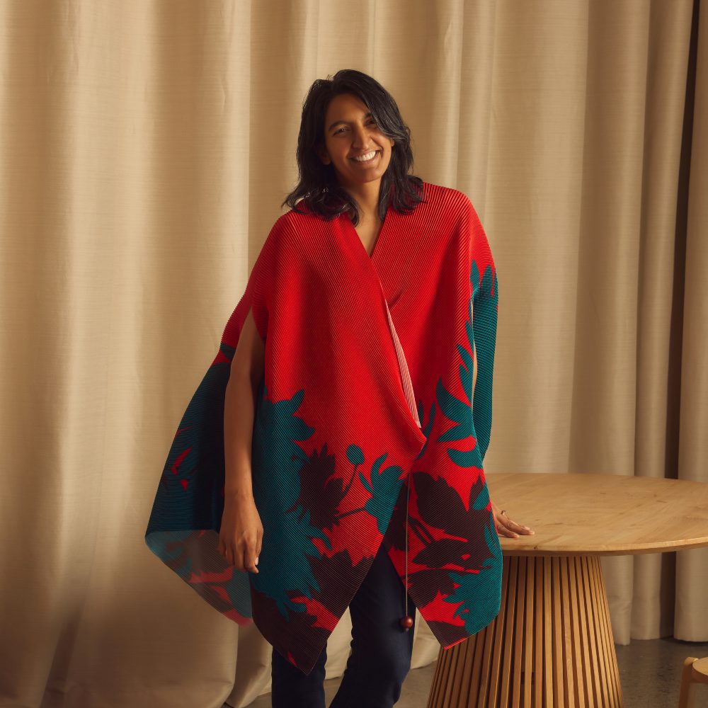 Ami Vora, chief product officer at Faire, wearing a red shawl and leaning on a table 