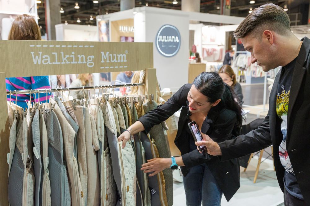 A man filming a woman showing baby products on a stand at BKS + FIMI