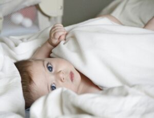 A baby lying in white bedding