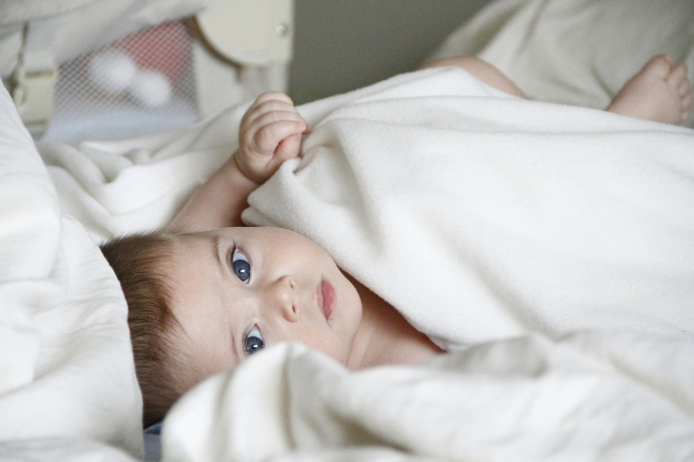 A baby lying in white bedding