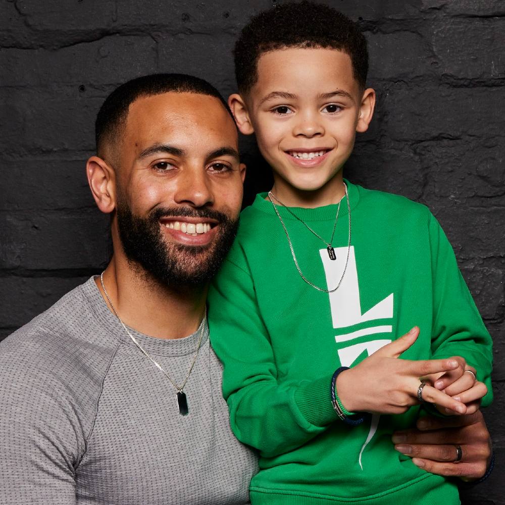 A man hugging a boy in a green top 