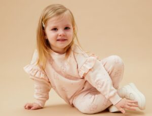 A young girl wearing a pink frilled top and trousers with Peppa Pig print on