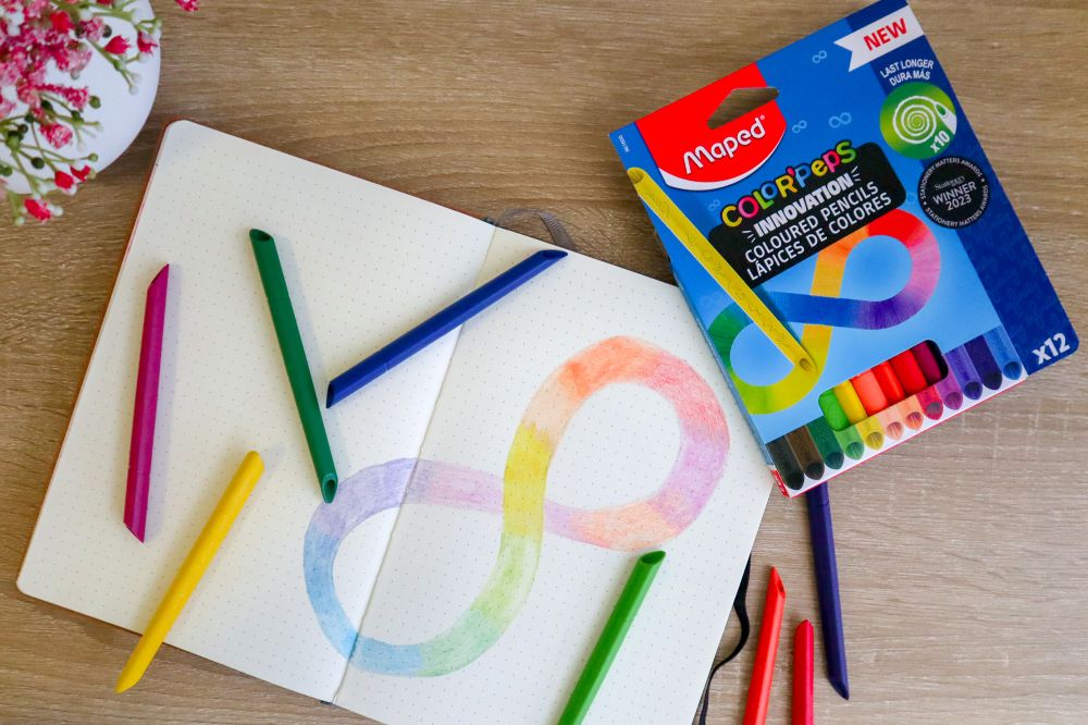 A box of Maped Helix Infinity Colouring Pencils beside a colouring book with an infinity symbol drawn on it