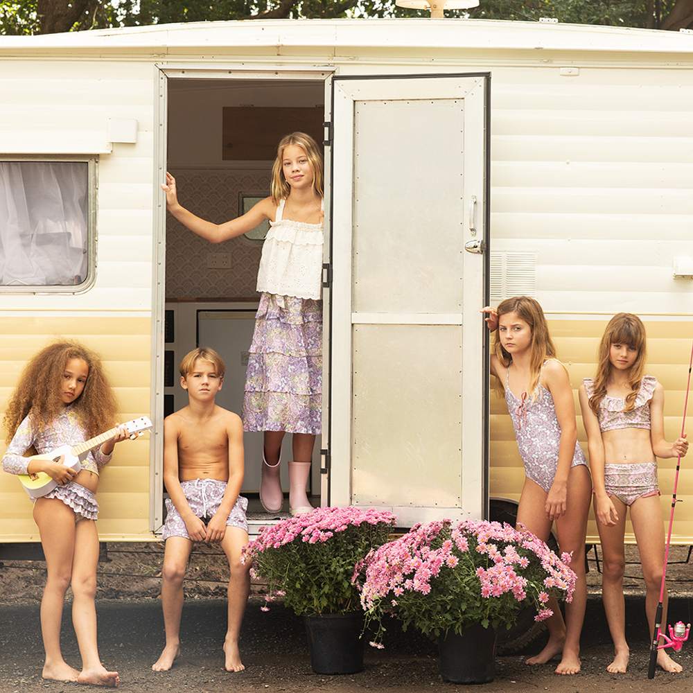 A group of children in swimwear stood outside a caravan 