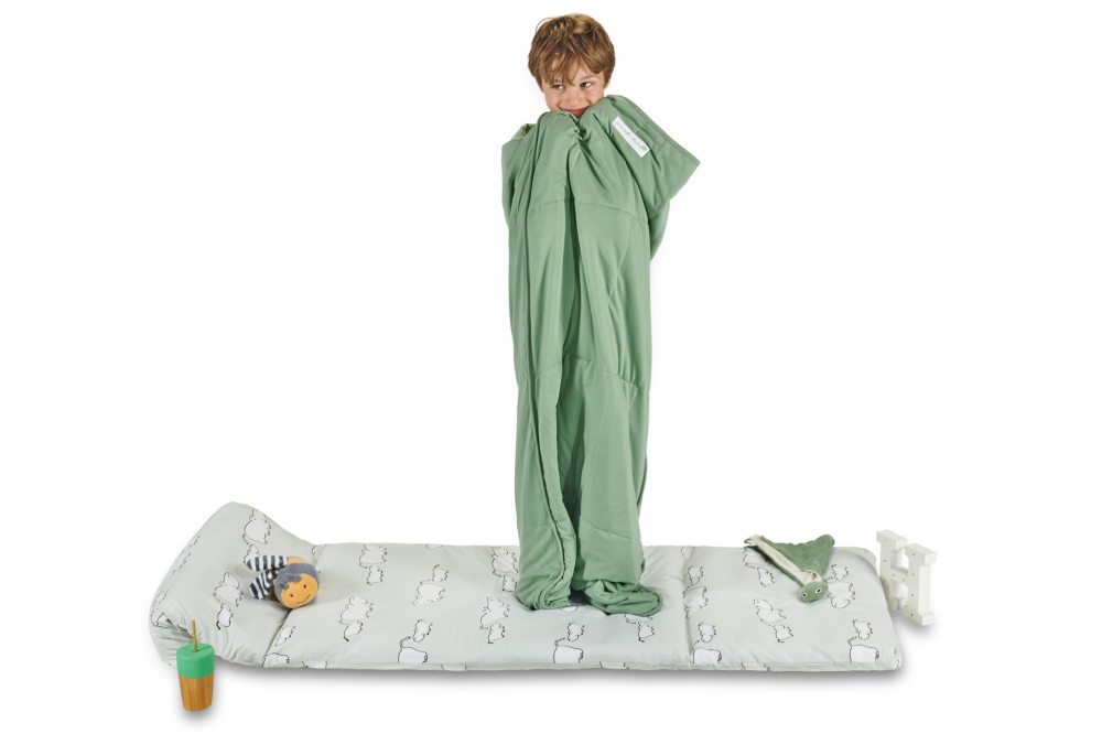 A young boy stood in a green sleeping bag 