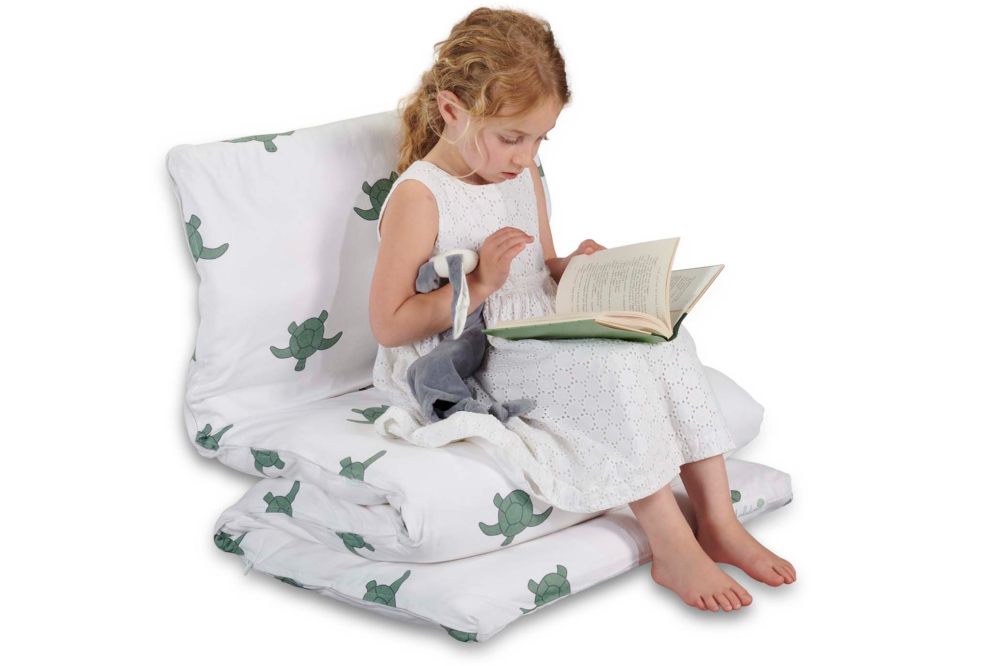 A young girl sat on a fabric chair reading a book