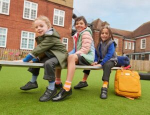 Three school children sat on a bench outside