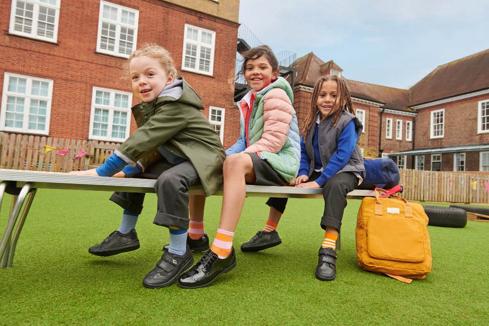 Three school children sat on a bench outside