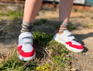 A young boy stood outside wearing a pair of red and white Glide trainers