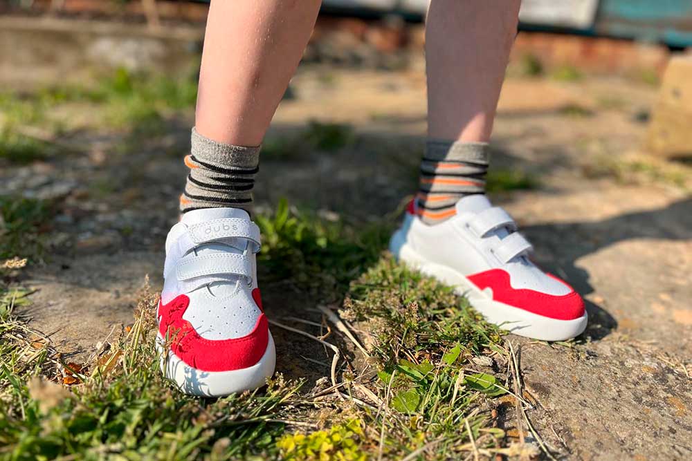 A young boy stood outside wearing a pair of red and white Glide trainers