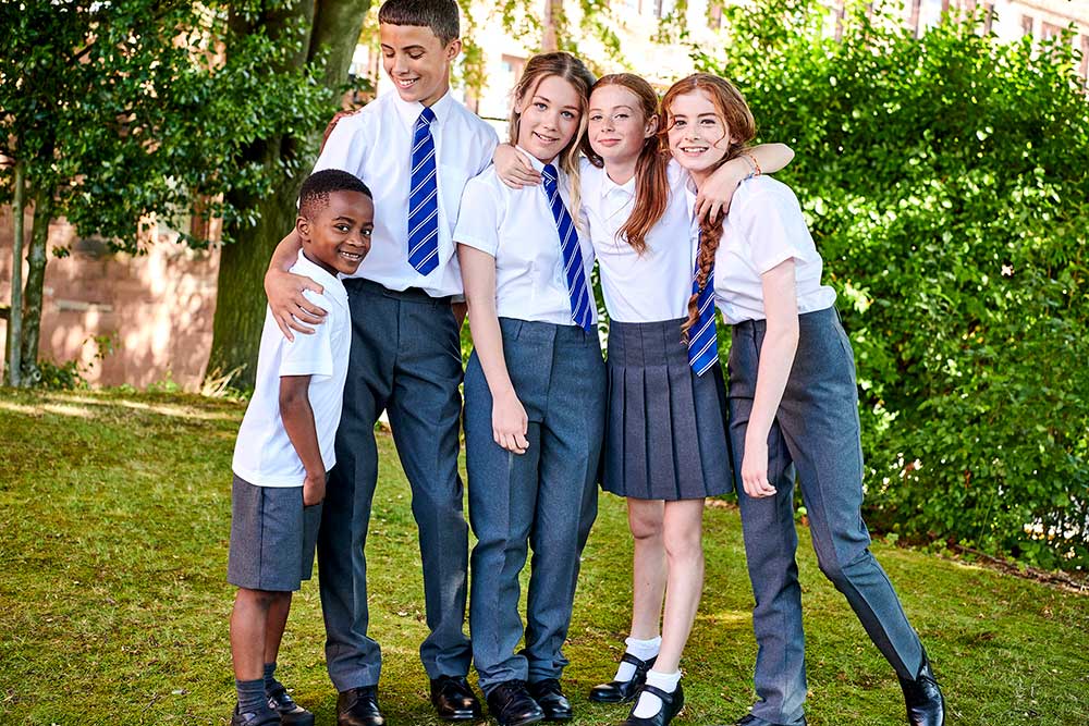 Five school children stood together outside a school