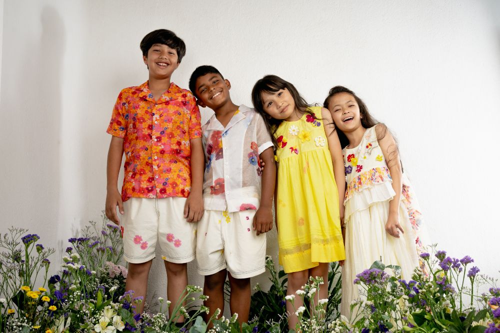 Four children stood in a row among flowers 