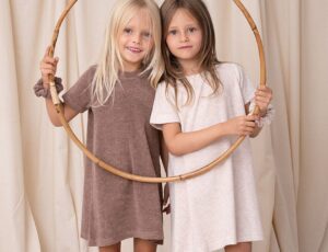 Two girls stood in front of a curtain holding a bamboo ring and wearing dresses by Bodi Loves