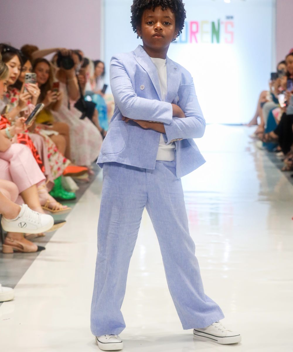 A boy on a fashion catwalk wearing a pale blue suit