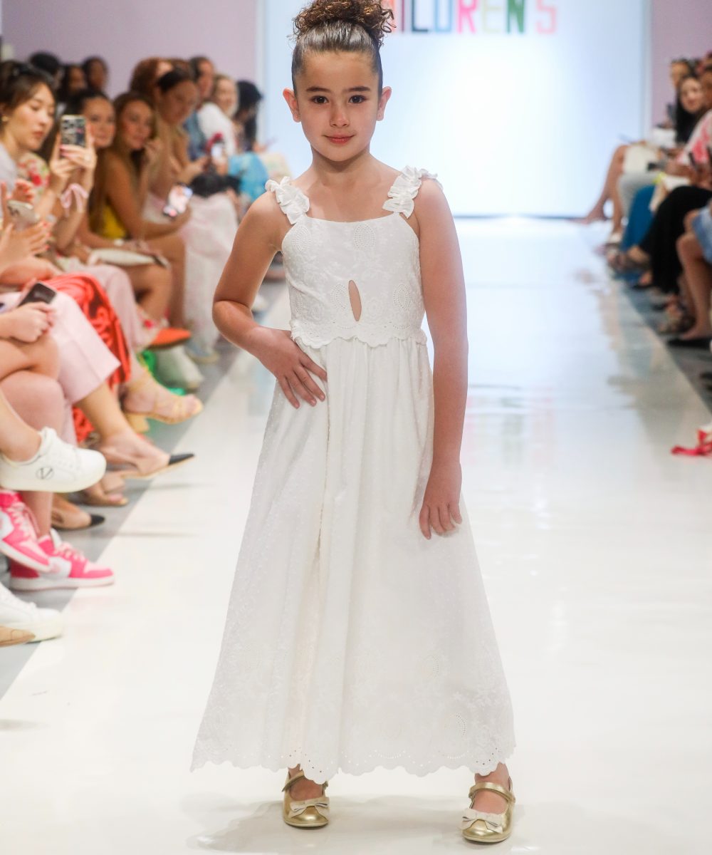 A girl in a white dress stood at the end of a fashion catwalk at Children's Show 