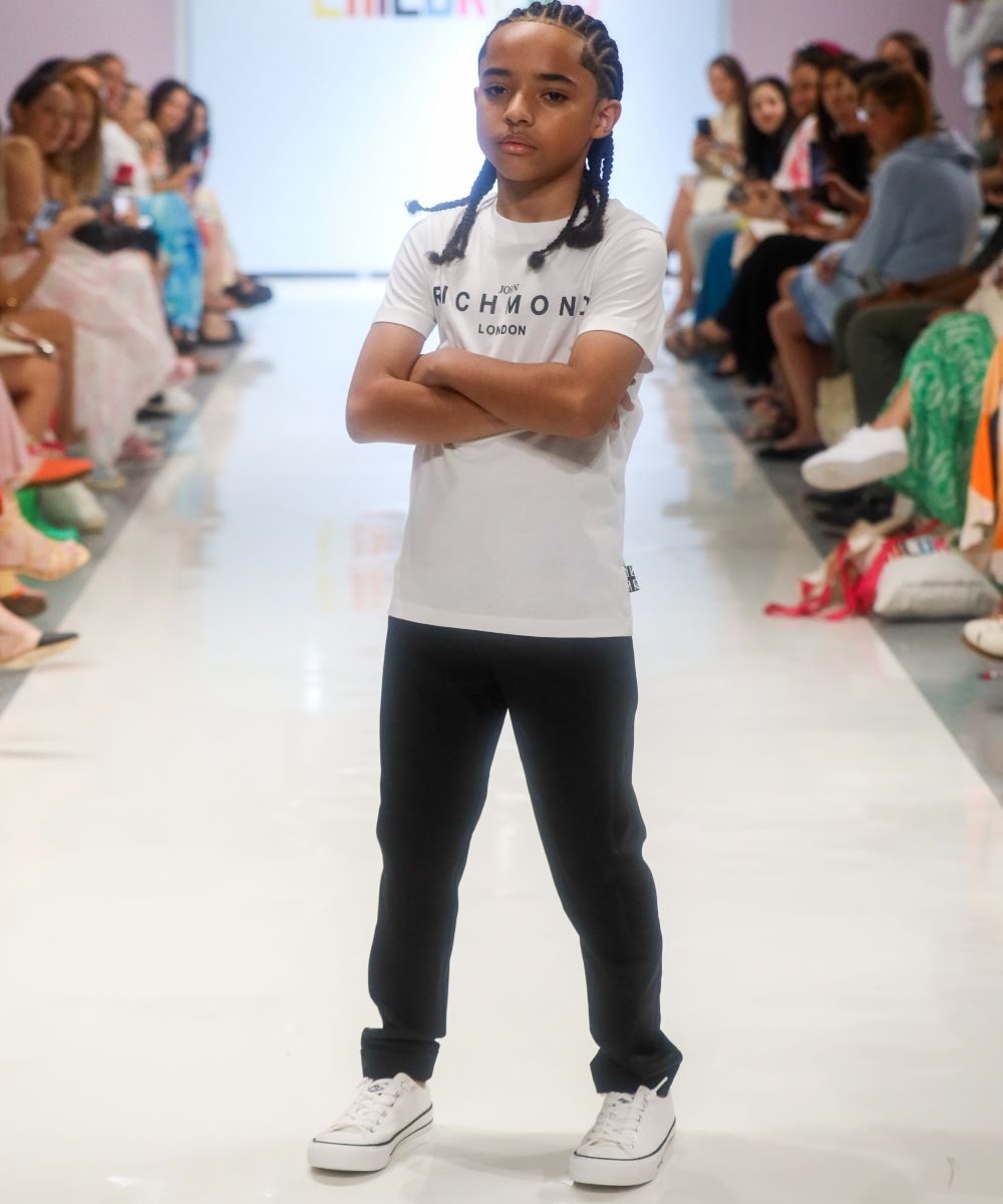 A boy in a white T-shirt and black trousers stood on a catwalk at Children's Show 