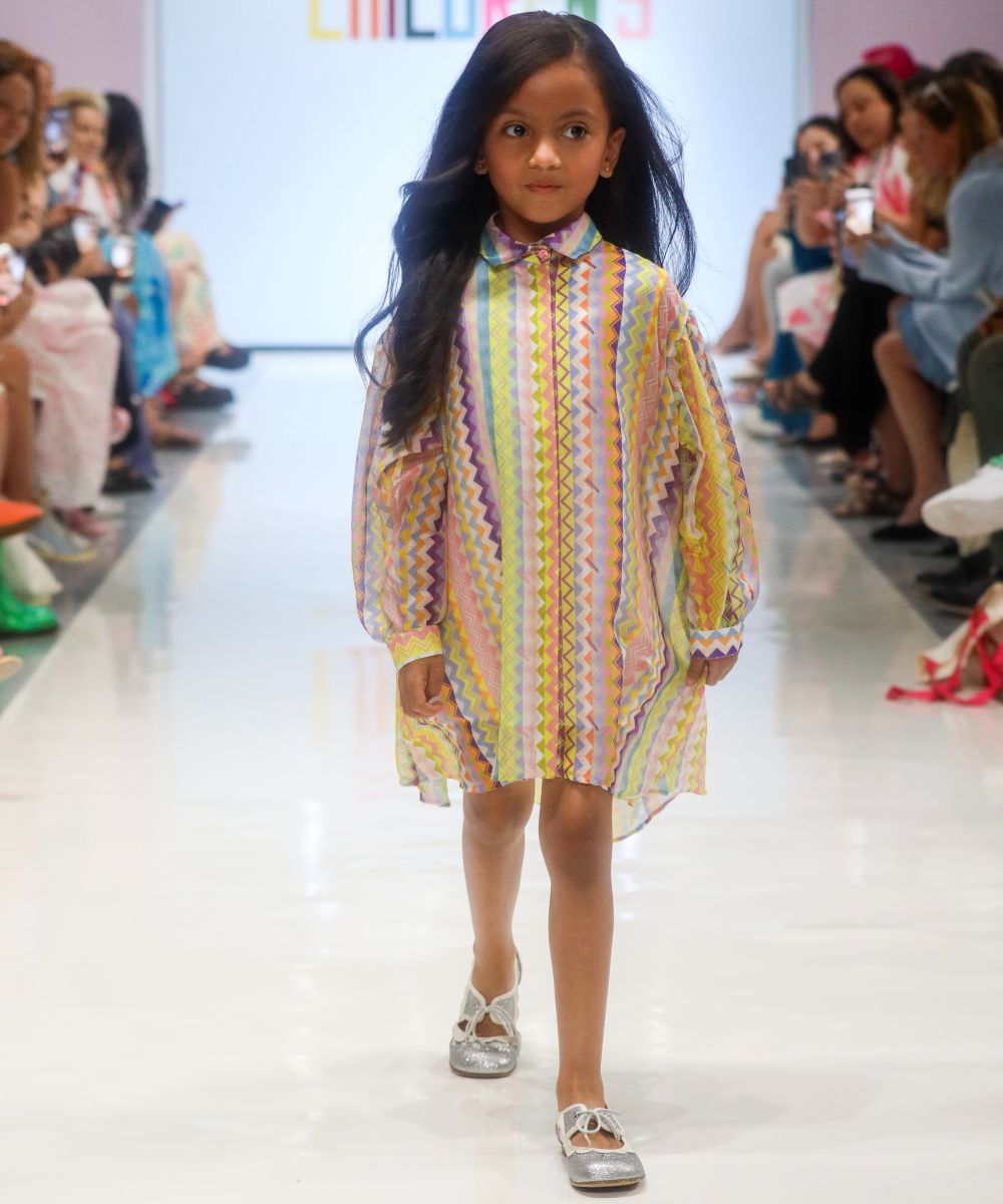 A young girl walking down a catwalk at Children's Show wearing a long sleeved Missoni dress