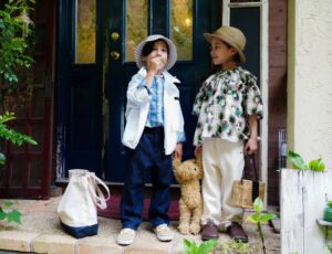 Two young boys in sun hats stood on the porch of a house