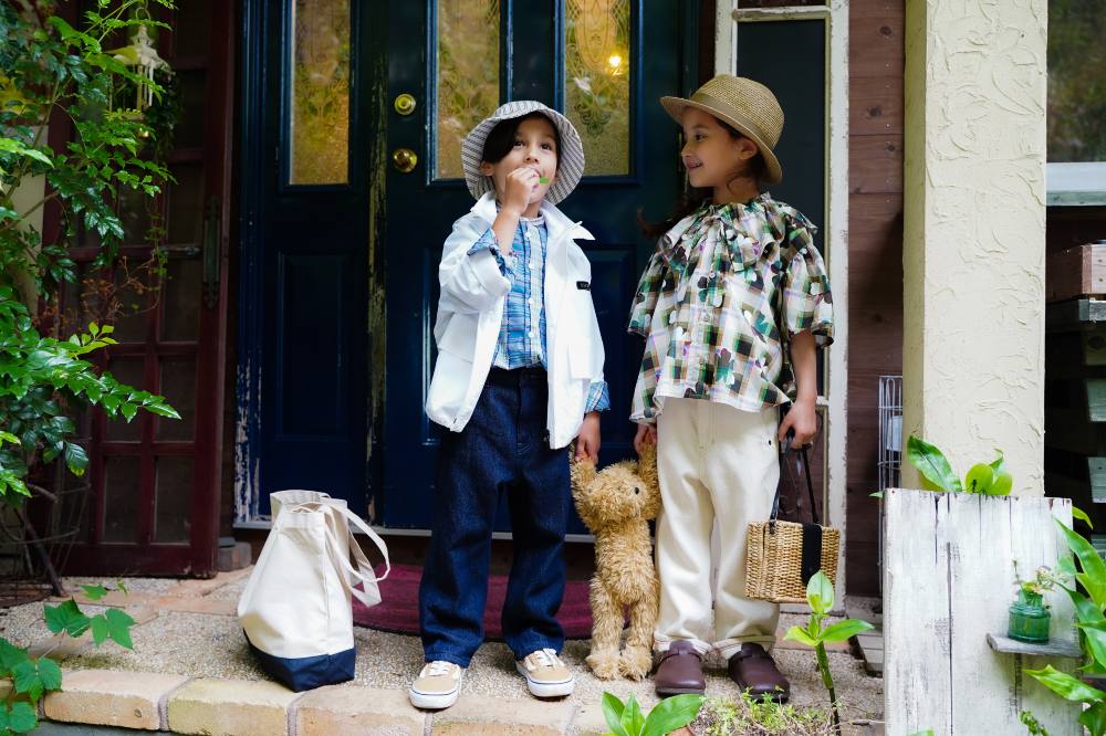 Two young boys in sun hats stood on the porch of a house