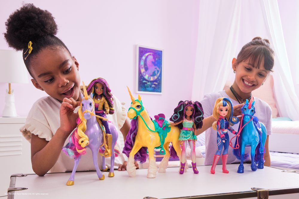 Two girls sat at a table playing with unicorn toys to illustrate INDX Toy & Gift show