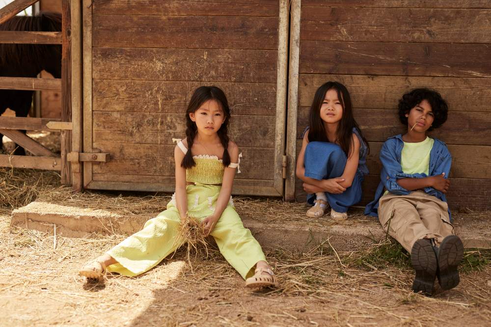 Three children sat on the floor outside a stable 