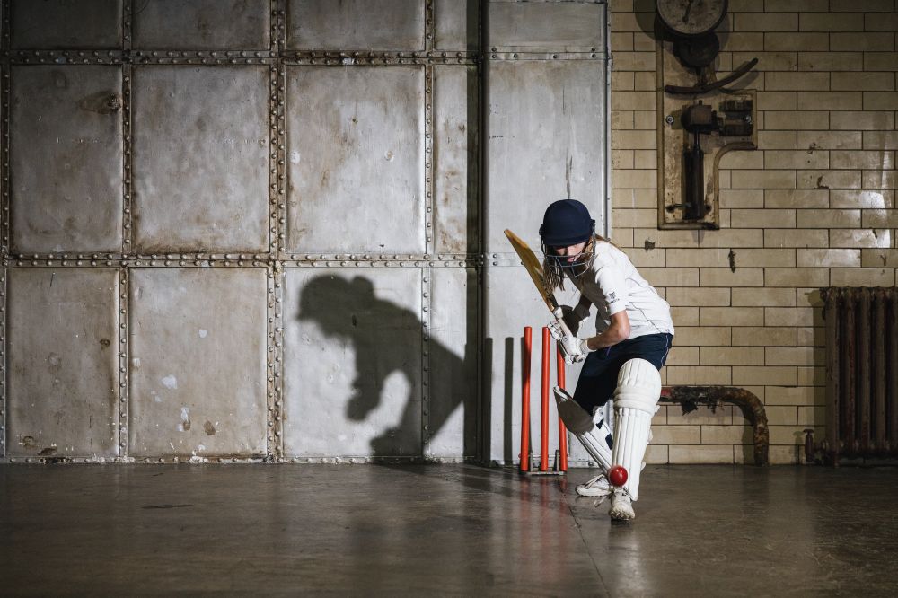 A young girl practising cricket indoors