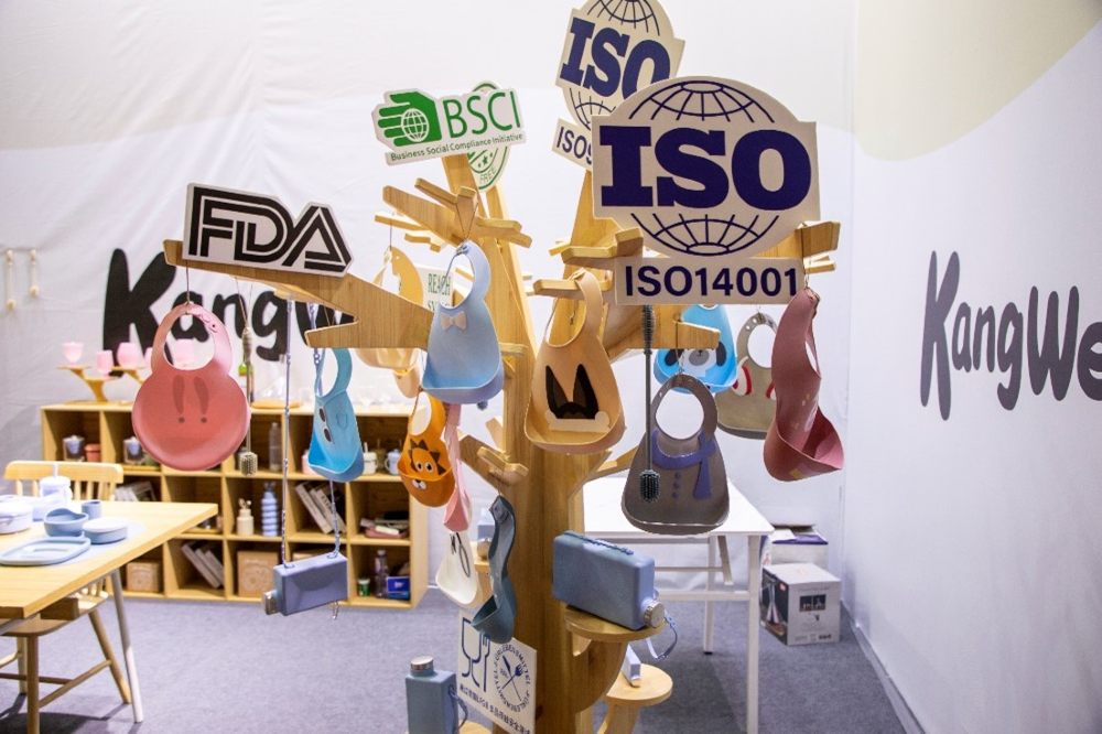 Children's bibs hung on a wooden tree display at the Maternal & Child Products Export Expo