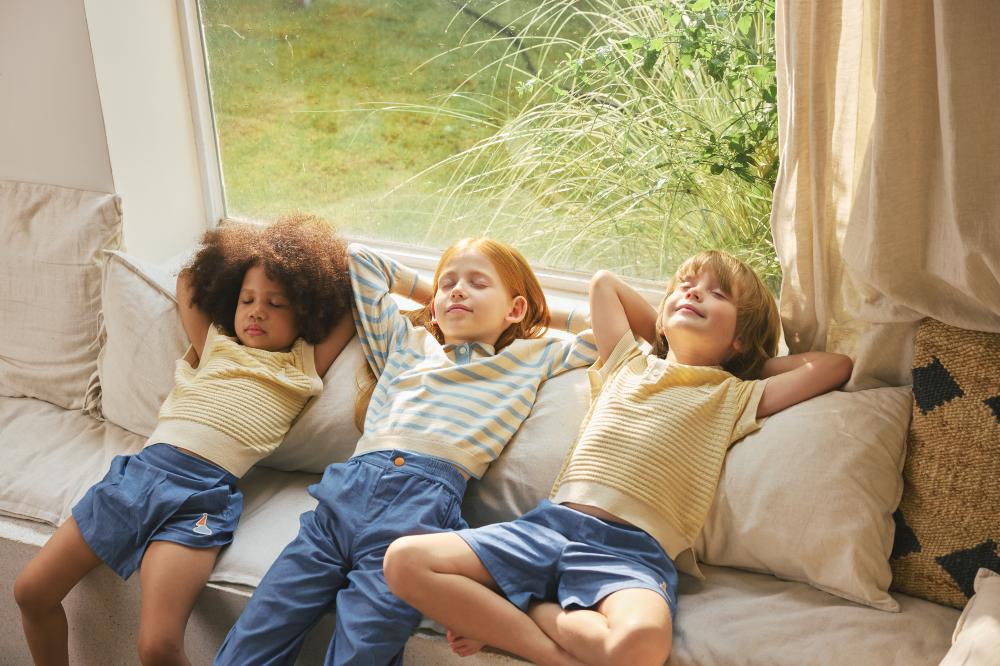 Three children lying back on a sofa 