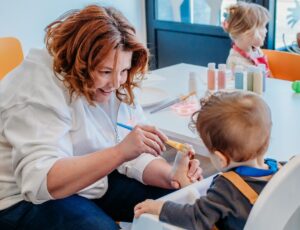 A woman feeding a baby in a highchair in a nursery