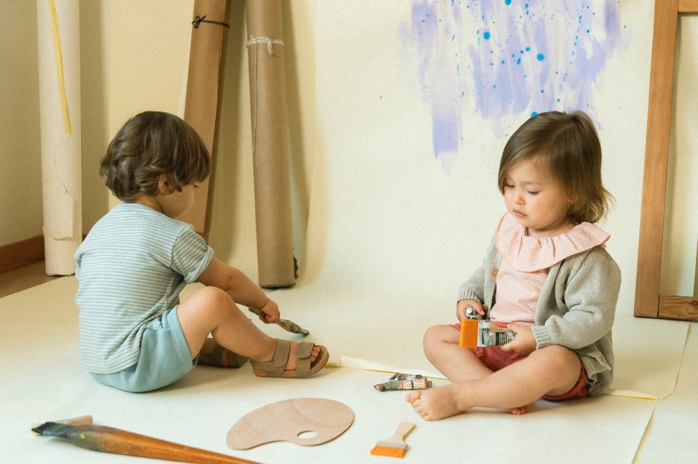 Two young children sat on the floor playing 