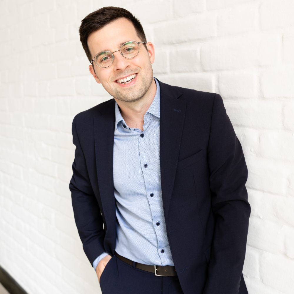 Stefan Eipeltauer of ARkid Studio stood in a suit and shirt against a white wall smiling at the camera 