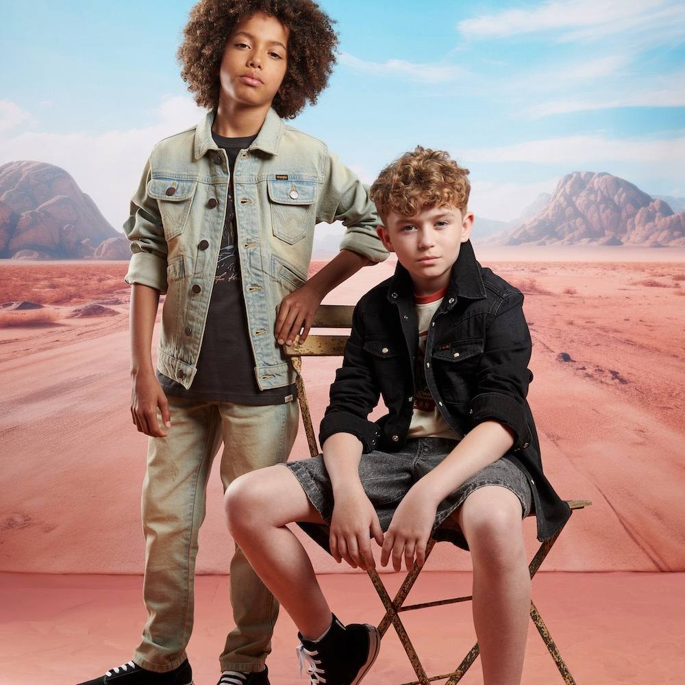 Two boys wearing outfits by Wrangler stood against a background of a desert road