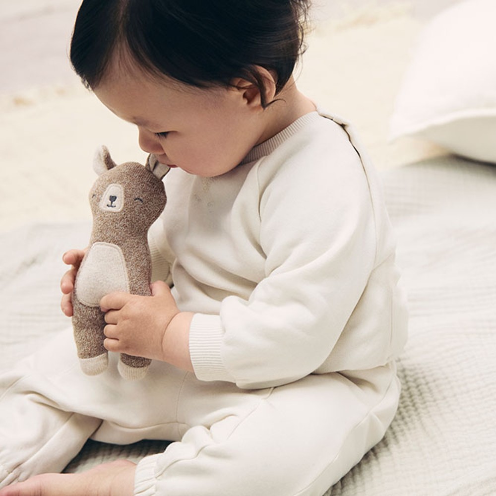 A young child sat on a bed holding a toy animal