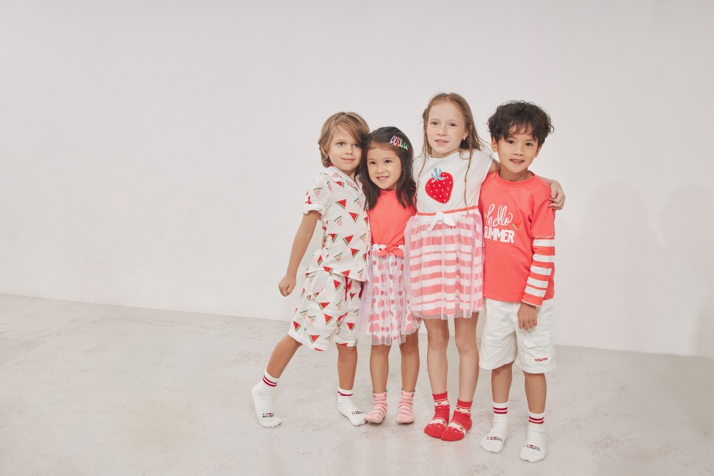 Four children stood together wearing summer outfits with fruit prints on them