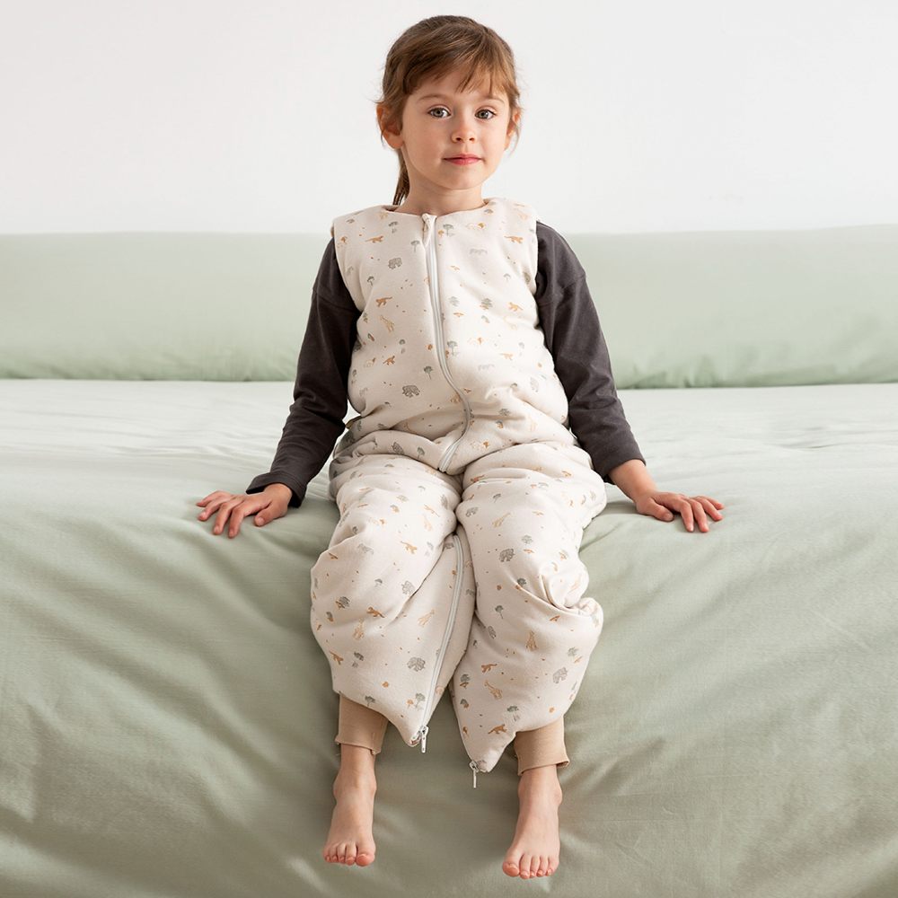 A girl sat on the edge of a bed in a sleepsuit 