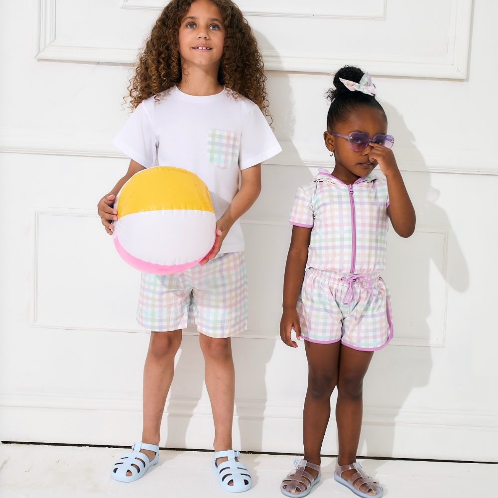 A young child holding an inflatable ball beside a young girl in purple sunglasses 