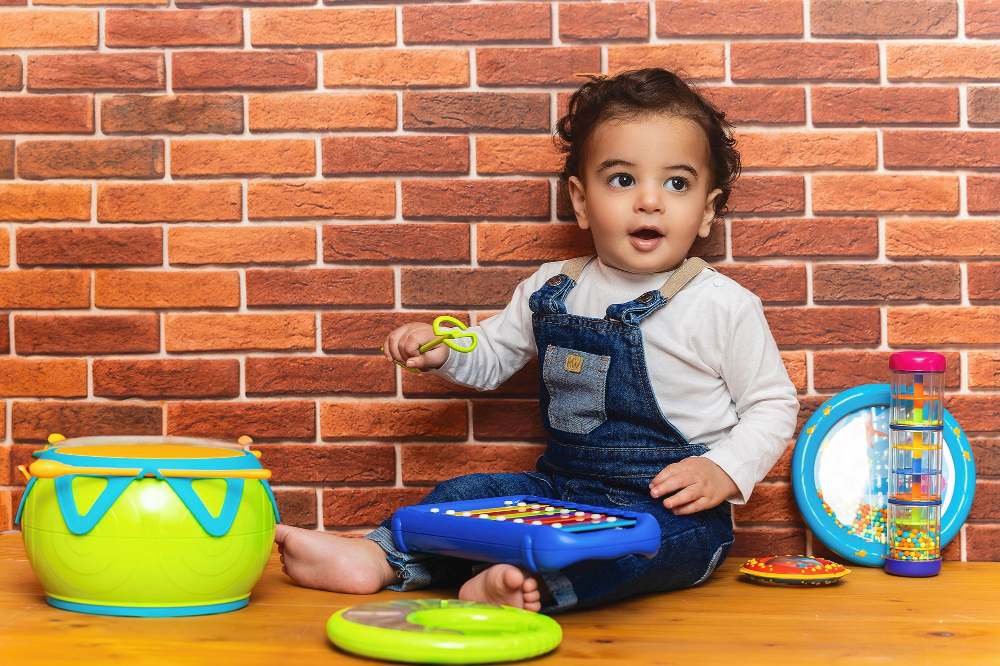 A young child sat on the floor with toy musical instruments 