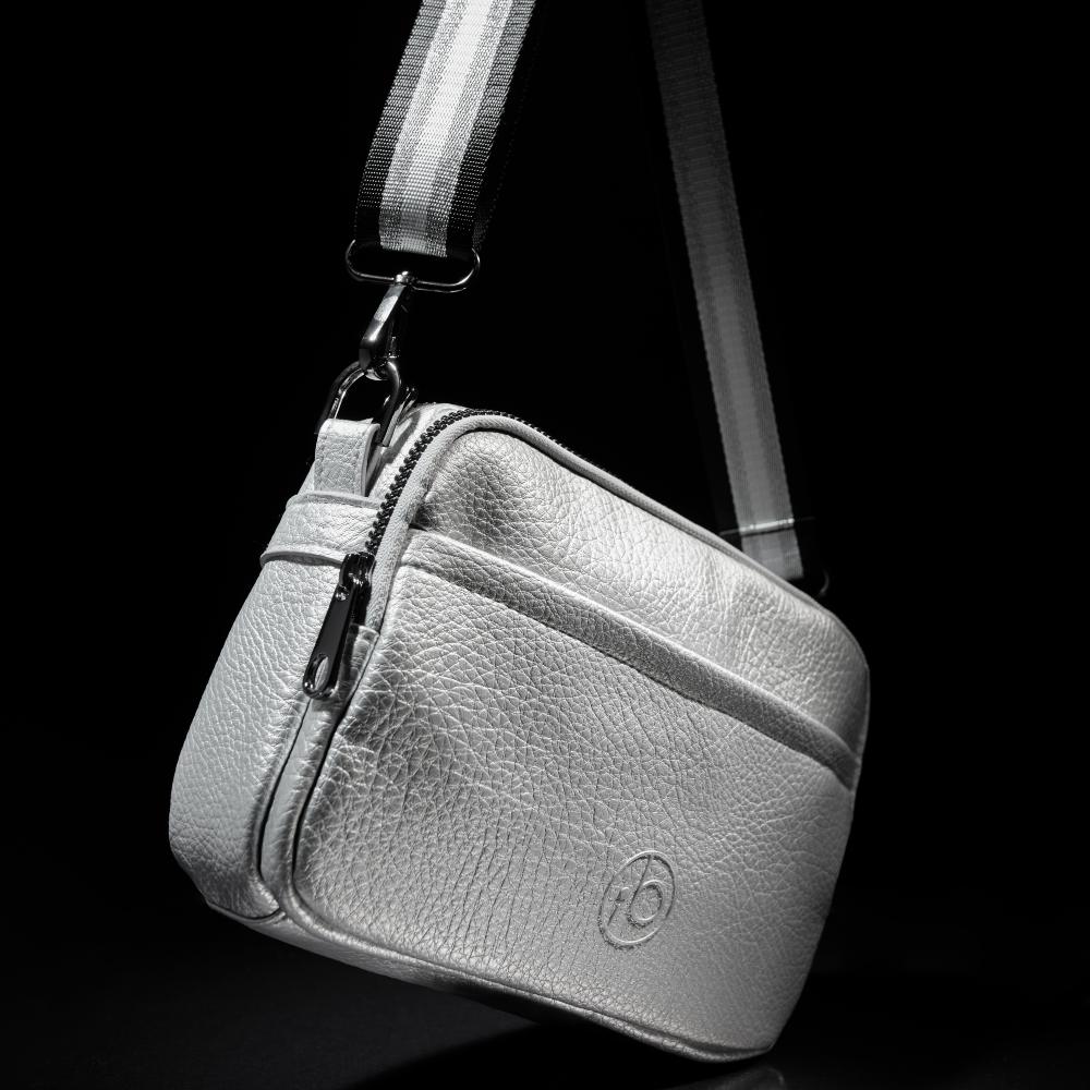 A silver changing bag from Ickle Bubba's Limited-Edition Chrome Collection hung against a black background