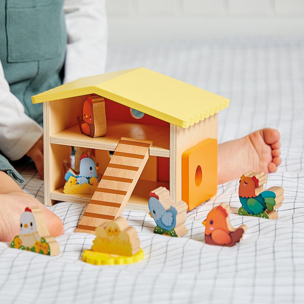 A young child sat beside a wooden farm toy set 