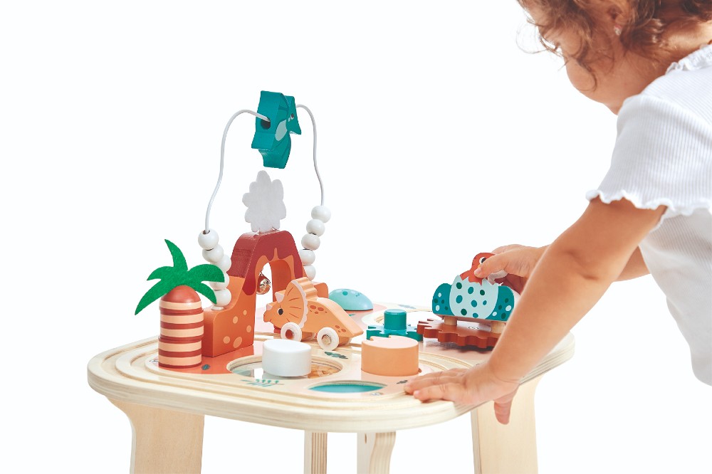 A child playing with the wooden Dino Activity Table by Jura Toys