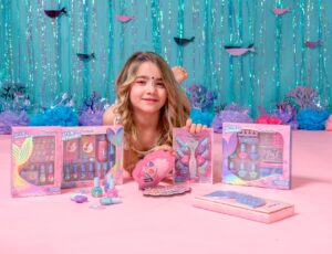 A young Girl lying on the floor with mermaid themed toys and gifts in front of her