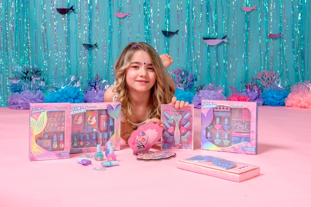 A young Girl lying on the floor with mermaid themed toys and gifts in front of her