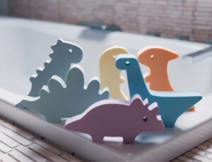 Children's dinosaur bath toys on the edge of a bath