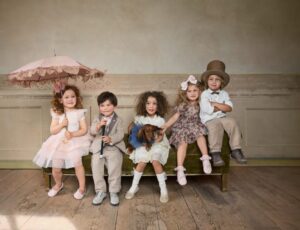 Five children sat on a bench in a room wearing outfits from Newbie's Vintage Circus Collection