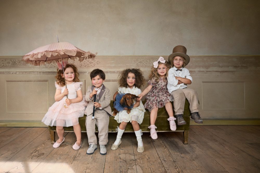 Five children sat on a bench in a room wearing outfits from Newbie's Vintage Circus Collection