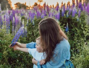 A woman holding a child sat in a field of purple flowers