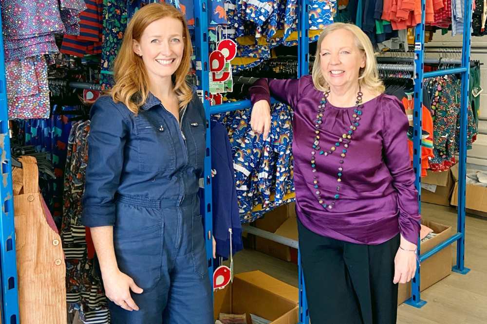 Thelittleloop founder Charlotte Morley stood beside Deborah Meaden with rails of children's clothes behind them