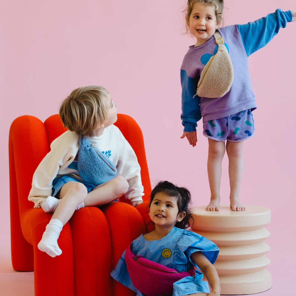 Three children wearing fluffy fanny packs