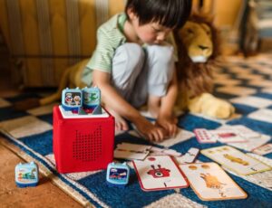 A young child sat on the floor playing with Alphablocks and Numberblocks Clever Pocket Tonie ranges